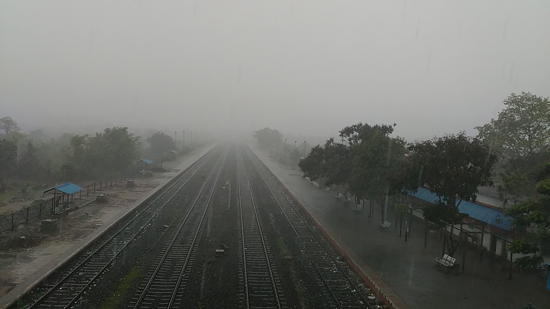 Railway tracks and a platform receding into mist after rain